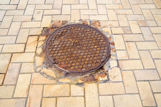 Metal sewer manhole in pavement closeup shot