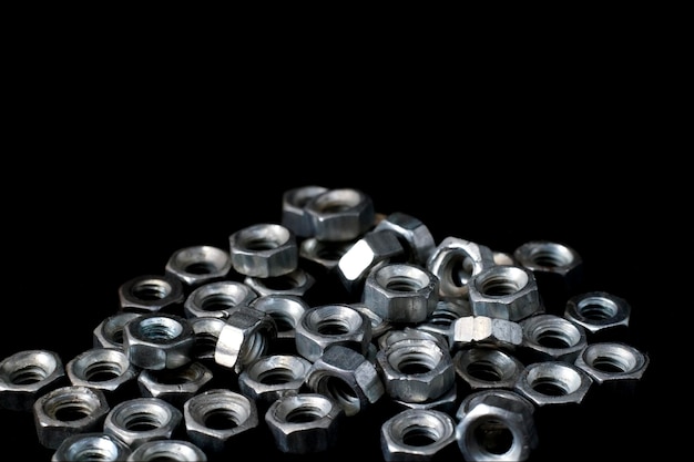 Metal shiny nuts on black background top shot metal hot dip galvanized finish nuts macro short nuts and bolts