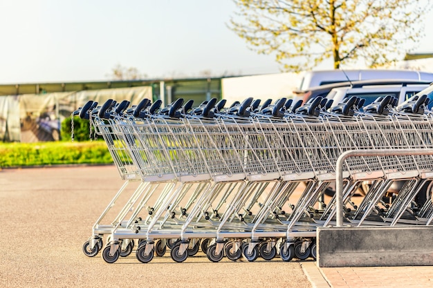 Metal shopping carts on a parking lot near supermarket