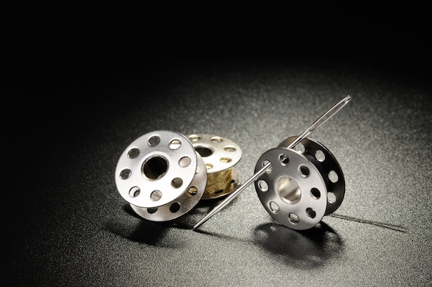 Metal spools of sewing machine on a black background