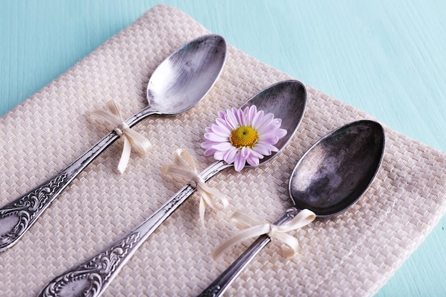 Metal spoons and camomile on napkin on light blue wooden background