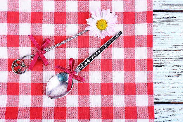 Metal spoons on checkered napkin on light blue background