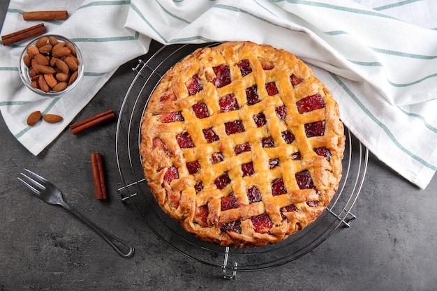 Metal stand with delicious berry pie on gray background