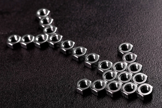 Metal steel nuts laid in composition on a dark table