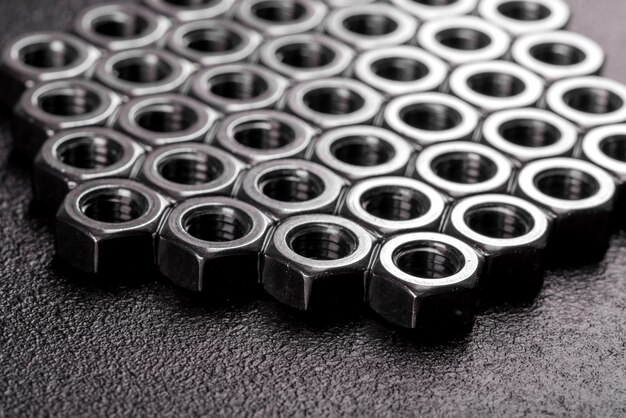 Metal steel nuts laid in composition on a dark table