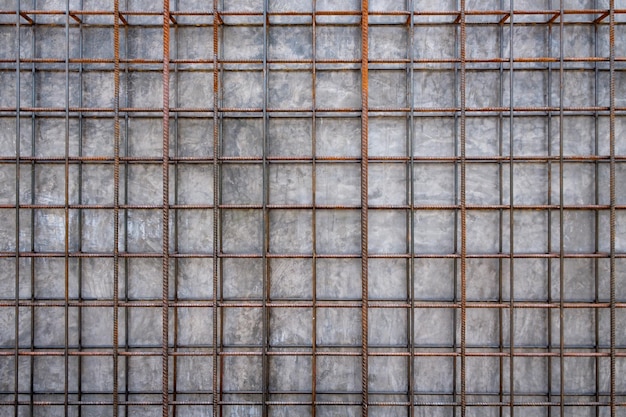 金属鋼の鉄筋の格子とコンクリートの壁の背景