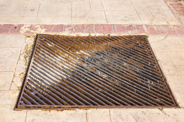 Metal storm drain with water running into it.