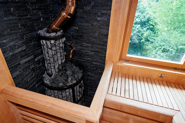 Metal stove filled with stones with a pipe in a wooden sauna