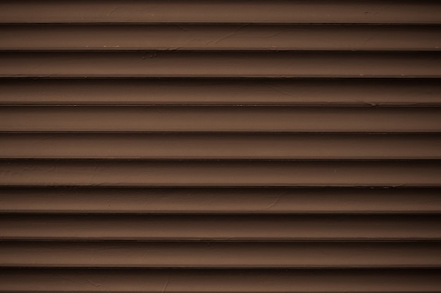 Metal striped pattern. Dark brown ribbed siding texture. Lines of fence, abstract grooved background.
