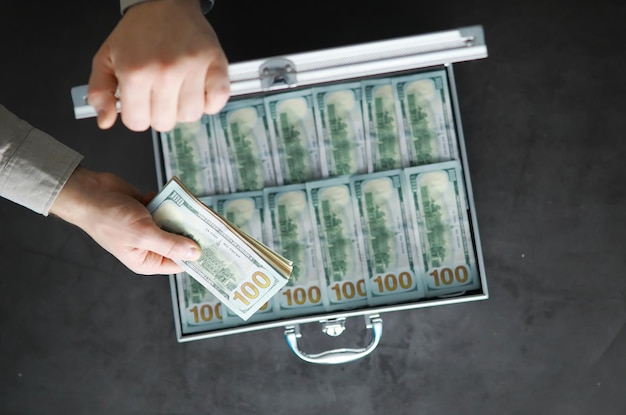 Una valigia di metallo riempiva banconote da 100 dollari americani. esposizione doppia. investimento, corruzione, concetto di corruzione.