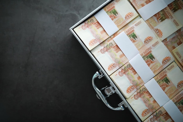 5000ルーブルのロシア紙幣で満たされた金属製のスーツケース。投資、賄賂、汚職の概念。