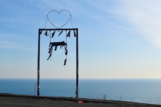 metal swing on the romantic mountain against the background of the sea and sky