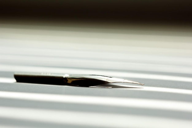 白い机の上の太陽光線のひな形の白い背景にインク ペンの金属の先端をクローズ アップ サイド ビュー スペル レッスンと書道の演習テンプレート レイアウト背景マクロ