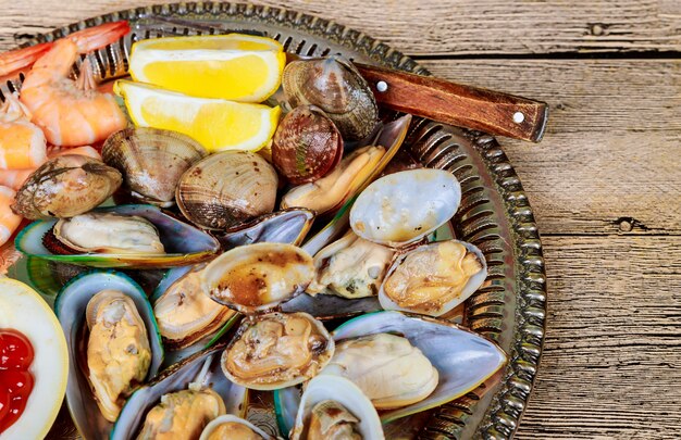 Metal tray with green mussels sauce over and Lemon