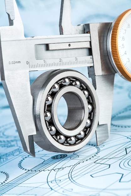 Metal vernier caliper and Ball bearings on technical drawing a blue toning