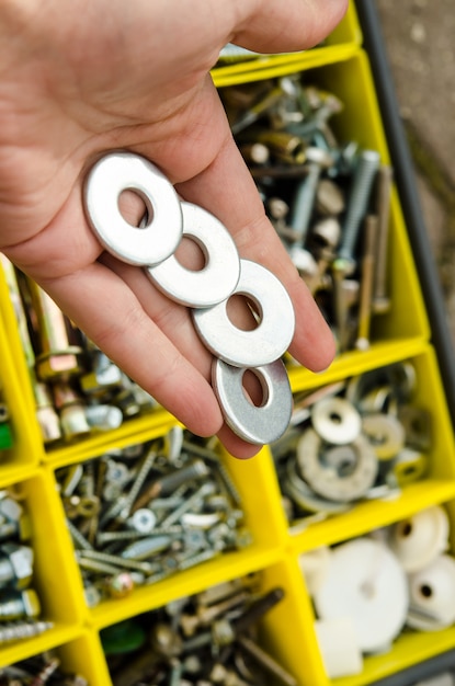 Metal washer in hand on the background of tools.