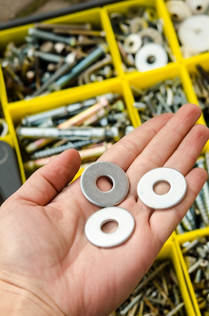 Metal washer in hand on the background of tools.