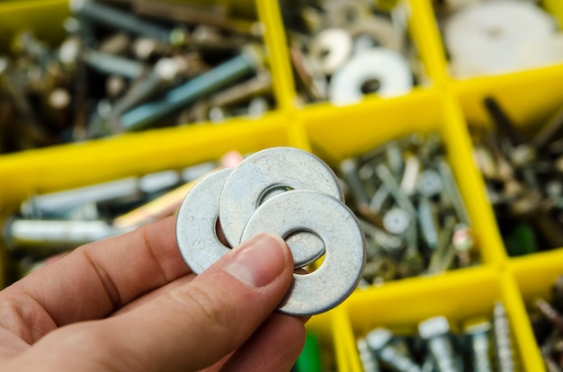 Metal washer in hand on the background of tools.