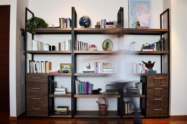 Photo metal and wood bookcase with drawers person in front passing