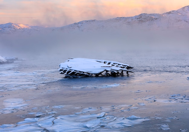 Metal and wooden parts of old ship seiners on the Barents Sea coast at sunrise. Teriberka, Kola Peninsula. Russia.