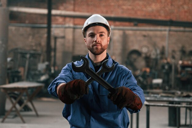 Фото Металлические ключи в руках фабричный работник в синей форме находится внутри