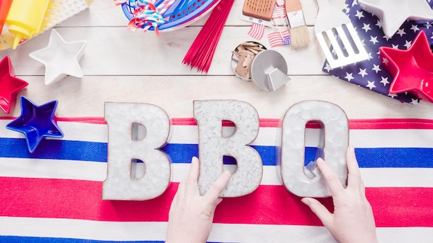 Metalen BBQ-bord met 4 juli-decoraties op een houten plank.