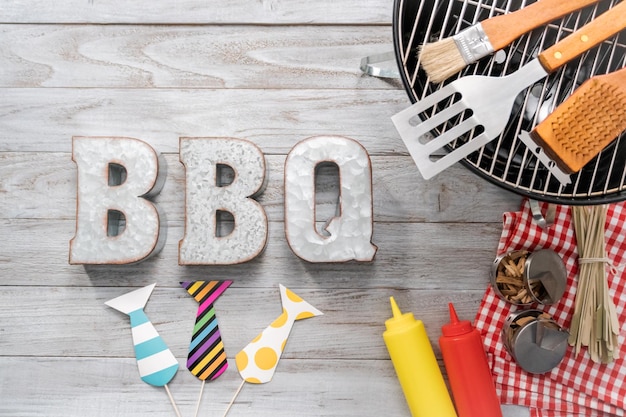 Metalen BBQ-bord met BBQ-kookgereedschap op een houten ondergrond.