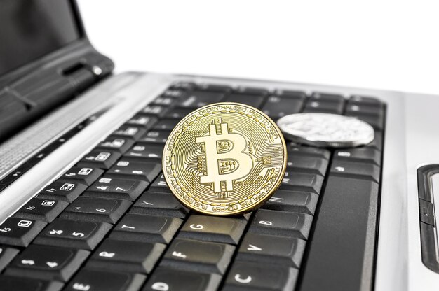 Metalen bitcoins op de laptop op witte achtergrond