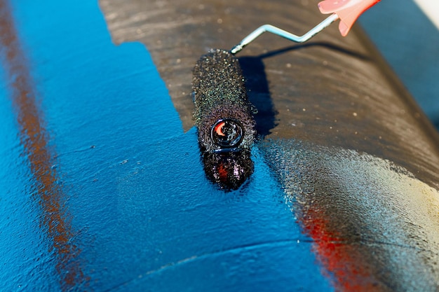 Foto metalen buizen worden met een verfroller geschilderd met zwarte verf voor de bescherming van metalen buizen tegen corrosie