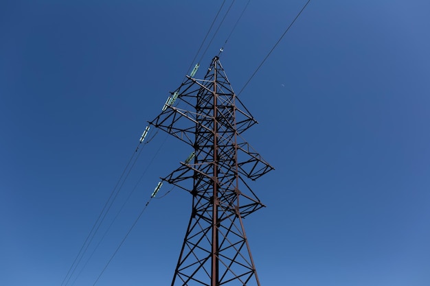 Metalen elektrische toren van hoogspanning op de achtergrond van de blauwe lucht Kleurrijke foto