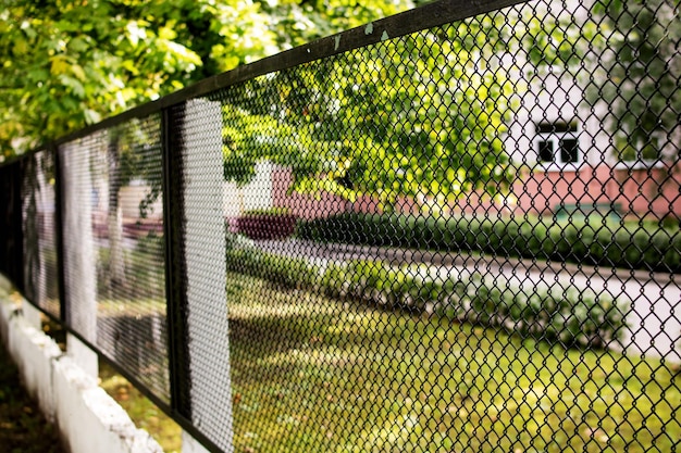 Metalen gaas hek op achtergrond van groene tuin