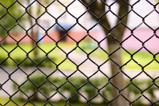 Metalen gaas hek op achtergrond van groene tuin