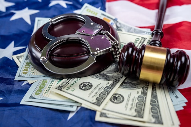 Metalen handboeien en de hamer en dollarbiljetten van een rechter liggen op een Amerikaanse vlag Concept van financiële misdaden of corruptie
