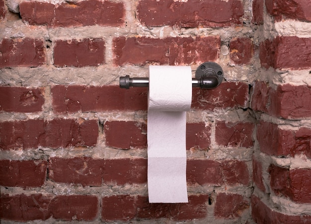 Metalen houder voor toiletpapier en papieren handdoekrol in loftstijl op bakstenen muur