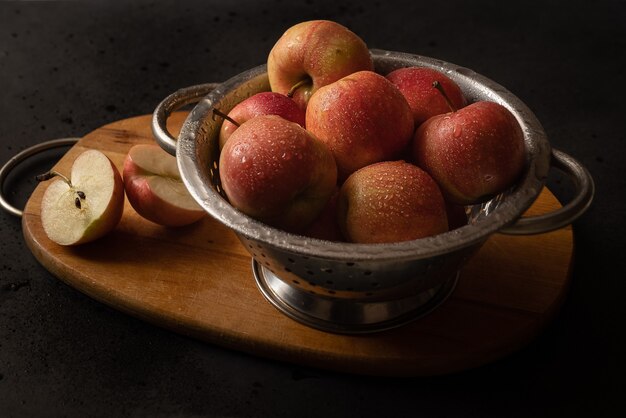 Metalen kom vol rode rijpe appels op houten snijplank stilleven. Appeltaart ingrediënten. Thuis koken