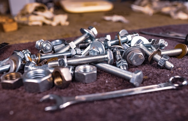 Metalen moeren en een sleutel liggen op de werktafel van de monteur