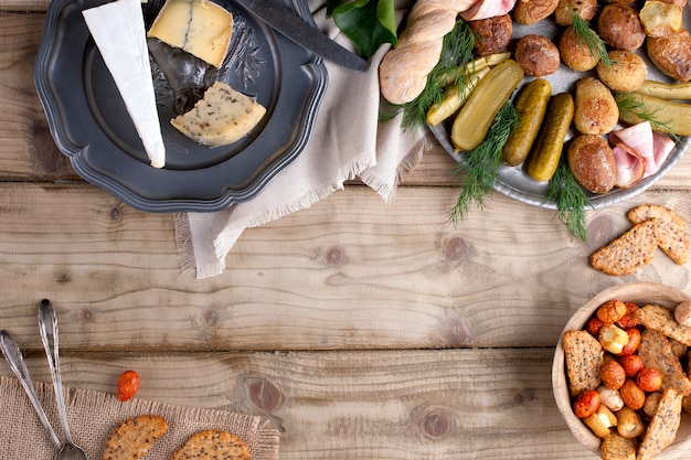 Foto metalen plaat met gebakken aardappelen en komkommers en greens, beschuit en kaas op een houten tafel