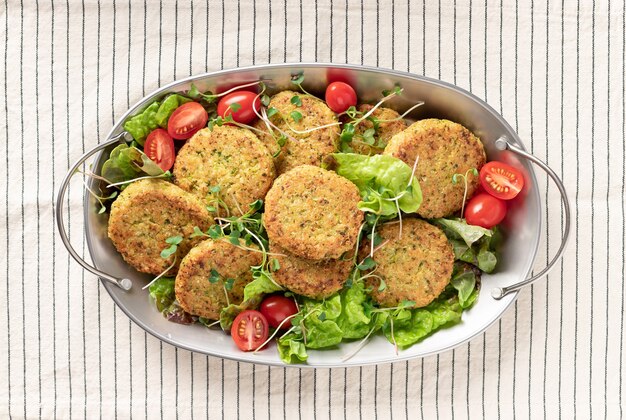 Metalen schaal met veganistische groenteburgers en salade