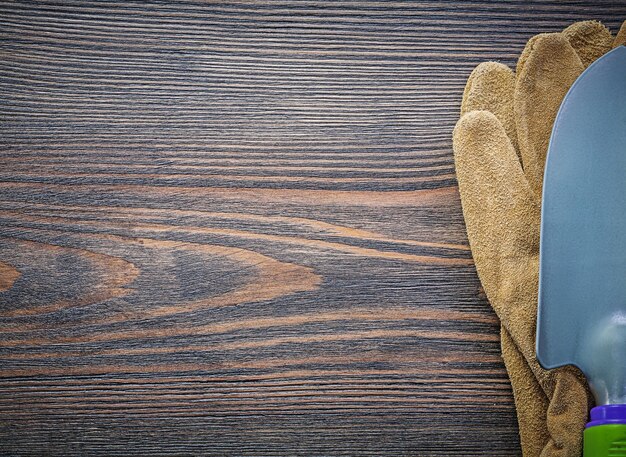 Metalen schop lederen veiligheidshandschoenen op houten plank kopie ruimte tuinieren concept