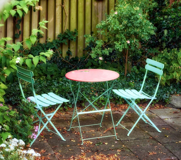 Metalen stoelen en tafel met bloeiende planten in een park of privébinnenplaats buitenshuis Rustig weelderig groen landschap en ontspannende plek in een tuin om te genieten van een gezellige picknick of een rustige middag in de lente