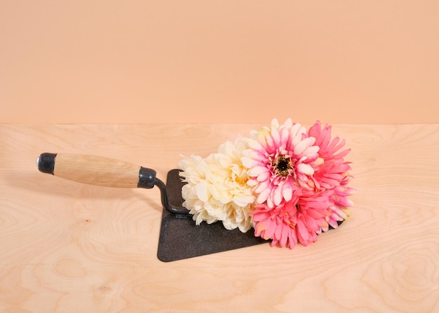 Metalen troffel met houten handvat ligt op het oppervlak Heldere zomerbloemen