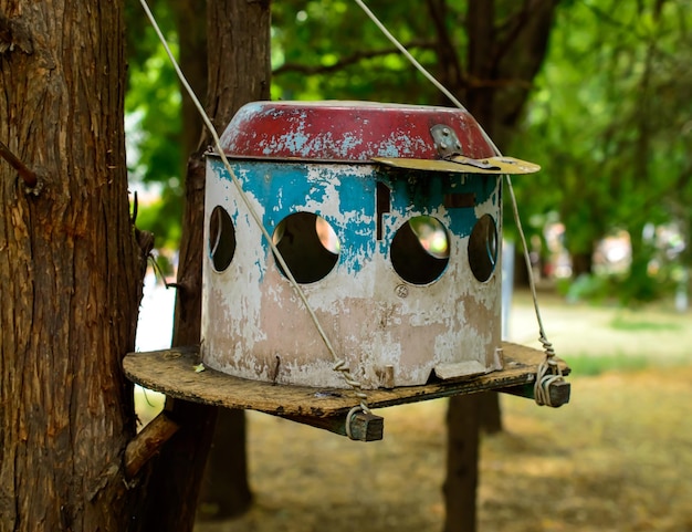 Metalen vogelhuisje of feeder bevestigd aan de boom in een park.