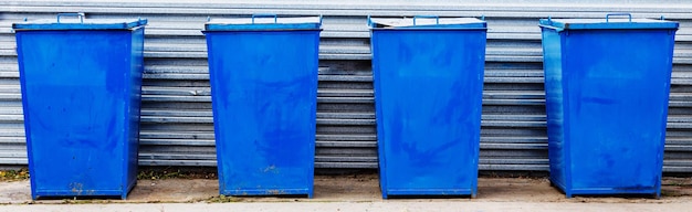 Metalen vuilnisbakken van blauwe kleur staan op een speciale plek in de open lucht op een zomerdag Afvalverwijdering