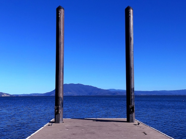 Foto bollardi metallici sul molo del lago contro il cielo blu
