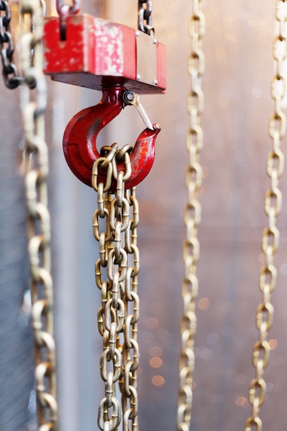 Metallic chain handle with red hook in technical room. Crane cargo hook.