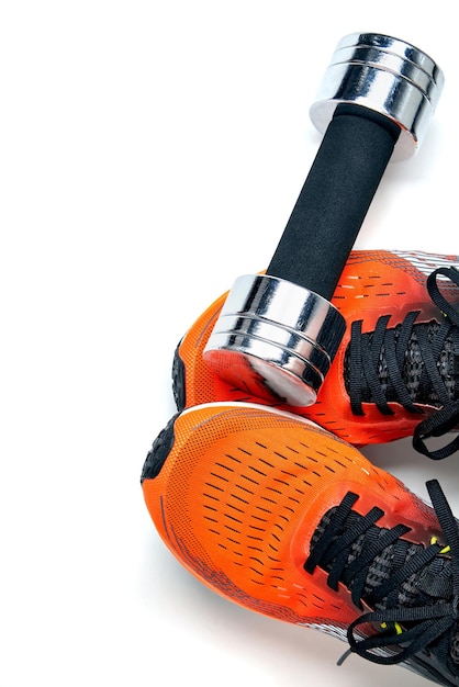 Metallic heavy dumbbell dropped on leg in orange sneaker isolated on white background