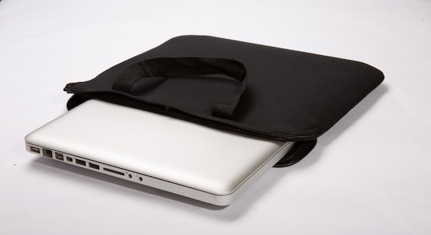 白い背景に分離された黒いコンピューター ケースに途中まで挿入された金属製のラップトップ