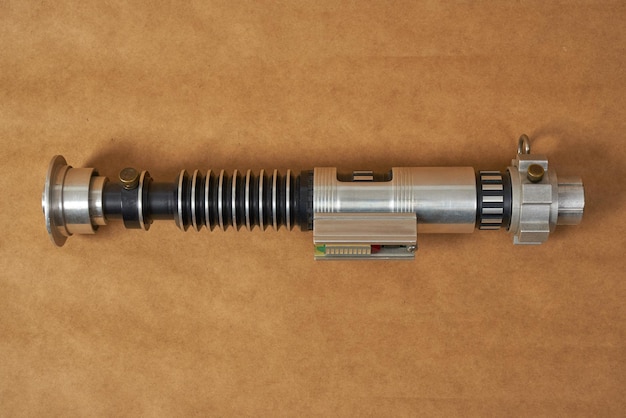 Photo metallic lightsaber on a brown background