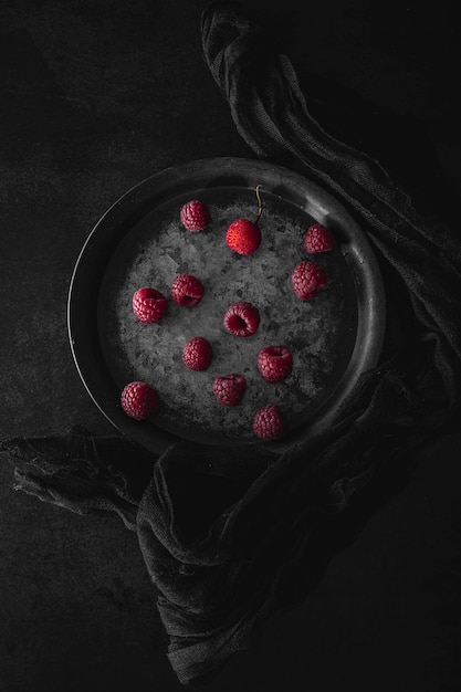 신선한 라즈베리가 있는 금속판. 복사 공간이 있는 어두운 분위기의 음식 사진