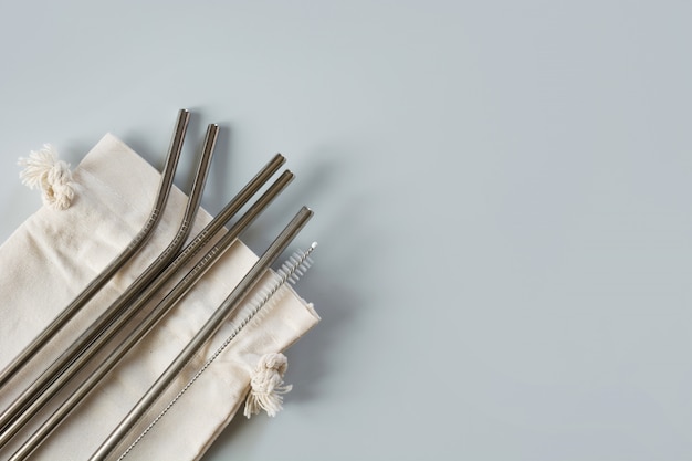 Metallic straws with cotton bag on grey.